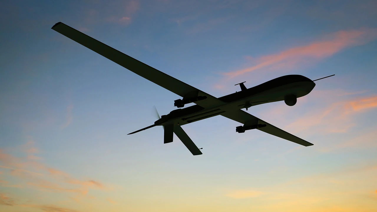Fixed-wing military unmanned aircraft flying at sunset, illustrating higher-capability drone threats and long-range payload delivery.